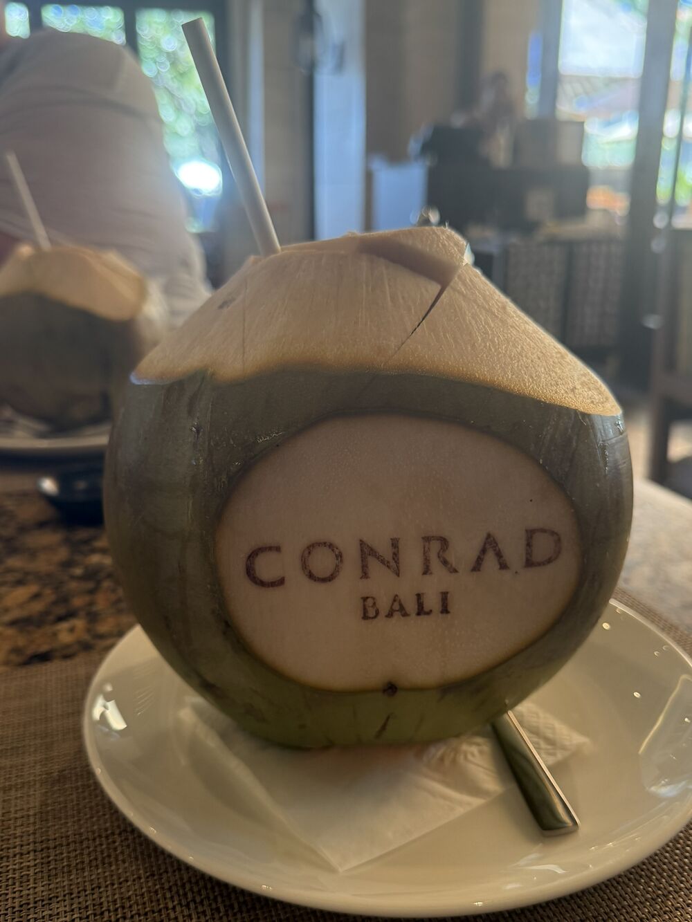 A fresh coconut branded Conrad Bali served at a breakfast table