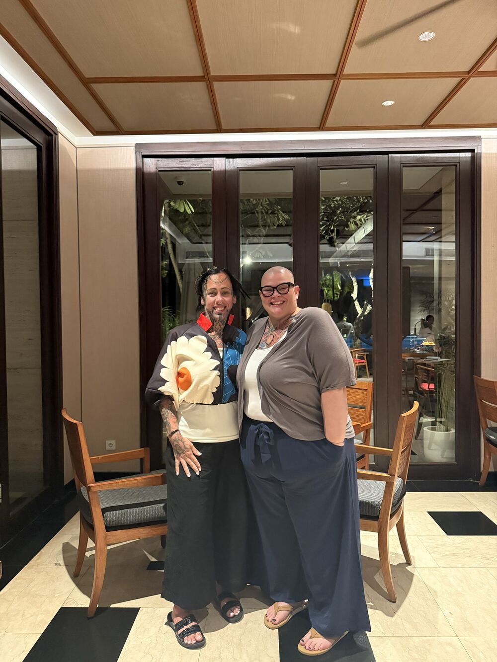 Cate and Jenna in a hotel lobby, one holding a bouquet of flowers