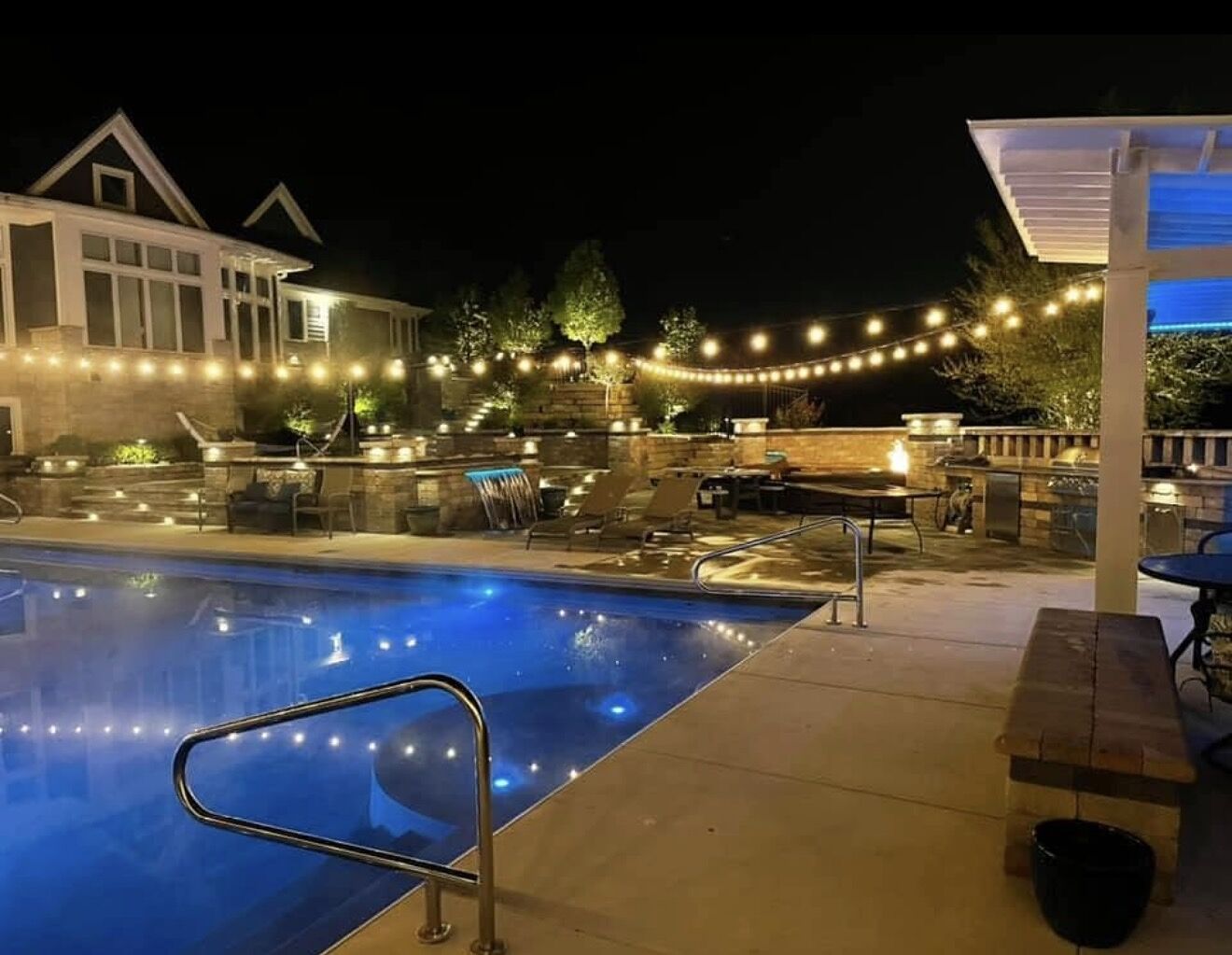 A resort pool at night under strings of warm festoon lights
