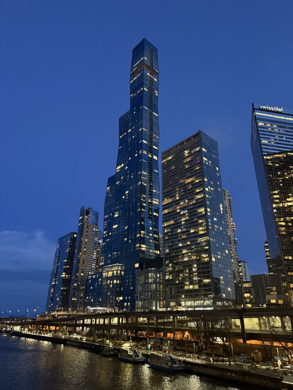 Glass towers lit up against a deep blue evening sky
